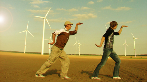 Zwei junge Männer posieren vor einem Windpark