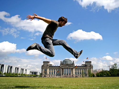 Ein junger Mann vollführt vor dem Bundestagsgebäude einen Luftsprung